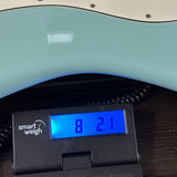 A close-up of a light blue electric guitar body resting on a black Smart Weigh scale displaying 8 lbs 2.1 oz.