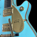 Close-up of a blue electric guitar with a Gretsch logo on the pickguard.