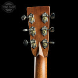 Close-up of the headstock of a wooden stringed instrument, showing six tuning pegs with decorative metal caps and a brown wood grain finish, set against a black background.