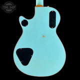 Back view of a turquoise electric guitar with 'Tone Shop' logo.