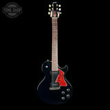 A black electric guitar with a red pickguard and chrome hardware, shown against a solid black background with a Tone Shop watermark in the top-left corner.