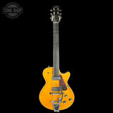 A yellow-orange electric guitar with a dark fretboard and chrome hardware, shown against a solid black background with a Tone Shop logo in the top-left corner.