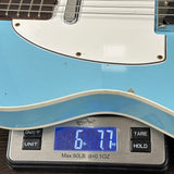 Blue electric guitar on a digital scale displaying weight.