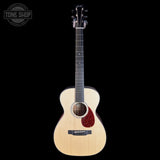A natural wood acoustic guitar with a dark reddish-brown pickguard, shown against a solid black background. A 'TONE SHOP' watermark is visible in the top-left corner.
