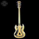 A custom acoustic guitar with a distinctive curved body, featuring a natural light wood finish with dark grain patterns, shown against a solid black background. A Tone Shop logo is visible in the top left corner.