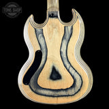The back of an electric guitar made of natural wood with a dark stained wavy inlay pattern, shown against a solid black background. A Tone Shop watermark is visible in the top left corner.