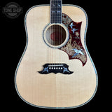 An acoustic-electric guitar with a natural wood body, featuring a decorative red and gold bird inlay on the upper bout, a black pickguard with matching bird motifs, and a dark fretboard, shown against a solid black background.