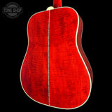 The back of an acoustic guitar with a vibrant red flamed maple top and cream-colored binding, shown against a solid black background with a Tone Shop watermark in the upper left.