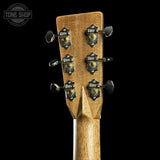 Close-up of the headstock of a guitar, showing six tuning pegs and decorative black-and-gold tuners on a natural wood finish, set against a solid black background with a Tone Shop watermark in the top left corner.