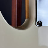 Close-up detail of a guitar body showing a cream-colored finish, a dark wood pickguard, and a silver metal hardware plate with a screw.