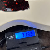 A close-up of a guitar body resting on a digital smart scale, showing the scale's blue display reading 7.133 kg.