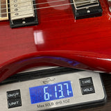 Red electric guitar on a digital scale displaying weight