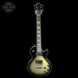 A Gibson Les Paul Custom electric guitar with a metallic gold-flecked black finish, shown against a solid black background. The Gibson logo is visible on the headstock, and a Tone Shop watermark is in the top-left corner.