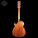 A back view of a wooden acoustic guitar against a solid black background, featuring a prominent grain pattern and a Tone Shop watermark in the top left corner.