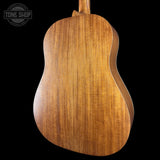Back view of a wooden acoustic guitar with 'Tone Shop' logo.