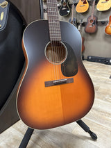 Acoustic guitar with a sunburst finish on a wooden floor.