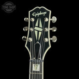 Close-up of a guitar headstock with 'Epiphone' branding on a black background.