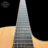 Close-up of an acoustic guitar's soundhole and fretboard with a black background.