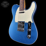 Blue electric guitar with a white pickguard on a black background, featuring the Tone Shop logo.