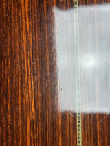 Close-up of a dark brown wood-grain surface with a decorative inlay stripe and visible scratches and glare.