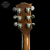 Close-up of the headstock of a vintage acoustic guitar, showing six silver tuning pegs on a dark brown wood finish, set against a solid black background with a Tone Shop watermark in the top left corner.