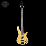 Electric bass guitar with a natural wood finish on a black background, featuring the Tone Shop logo.