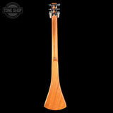 The back view of a wooden acoustic guitar showing its hollow body and neck, photographed against a solid black background with a Tone Shop watermark in the top left corner.