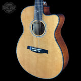A cutaway acoustic guitar with a natural wood top and dark brown sides, shown against a solid black background. A Tone Shop watermark is visible in the top-left corner.