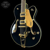 Black and gold electric guitar with 'Tone Shop' logo in the corner