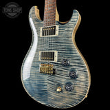 Blue electric guitar with a wavy wood finish on a black background, featuring the Tone Shop logo.