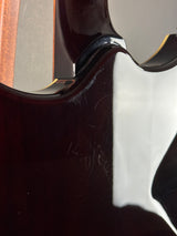 Close-up of a glossy dark brown electric guitar body showing the edge of the soundhole surround and some light scratches on the finish.