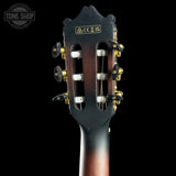 Close-up of the headstock of a classical guitar, showing the dark wood finish, six tuning pegs with gold accents, white tuning keys, and a gold brand plate with Chinese characters. The background is solid black.
