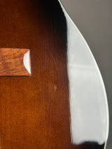 Close-up detail of an acoustic guitar body showing the glossy dark brown wood finish, a wooden bridge piece, and the curved edge of the soundboard.