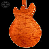 Close-up of a wooden guitar body with a visible brand logo in the corner.