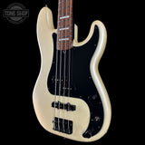 A Fender bass guitar with a cream-colored body, black pickguard, and black hardware, shown against a solid black background with a Tone Shop watermark in the top left corner.