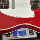 Red electric guitar on a digital scale displaying weight