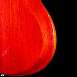 Close-up of a glossy red electric guitar body showing the wood grain finish and a small portion of the edge against a black background.