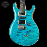 Turquoise electric guitar with a 'Tone Shop' logo in the corner.