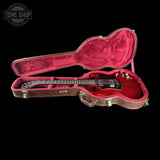 Red electric guitar in an open case on a black background with 'Tone Shop' logo.