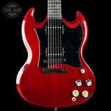 Red electric guitar with a black pickguard on a black background, featuring the Tone Shop logo.
