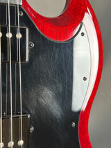 Close-up of a red and black electric guitar with a focus on the headstock and fretboard.