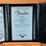 A black leather Fender instrument authenticity certificate insert displayed open, showing a silver certificate with gold and black Fender branding and text for a B4 LTD P.J.