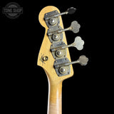 Close-up of the headstock of a bass guitar with a natural wood finish and four vintage-style metal tuners with flower-shaped pegs, shown against a black background.