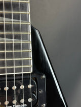 Close-up of a black electric guitar with visible brand name on a dark background
