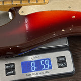 Close-up of a guitar body resting on a digital scale displaying 8 lbs 5.9 oz.