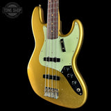 A gold-finished electric bass guitar with a pale mint green pickguard, black control plate, and dark wood fretboard, shown against a solid black background. A Tone Shop watermark is visible in the top left corner.