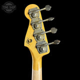 Close-up of the headstock of a vintage electric bass guitar with a natural wood finish, four metal tuners, and a Tone Shop logo in the top left corner, set against a solid black background.