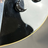 Close-up of a skateboard with a black deck and silver trucks.