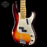 A classic four-string electric bass guitar with a sunburst finish, featuring a dark red outer edge fading to a bright orange and yellow center, a cream pickguard, and a maple neck, shown against a solid black background.
