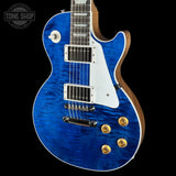 A blue flamed maple top electric guitar with a white pickguard and gold hardware, shown against a black background with a Tone Shop watermark in the top left corner.